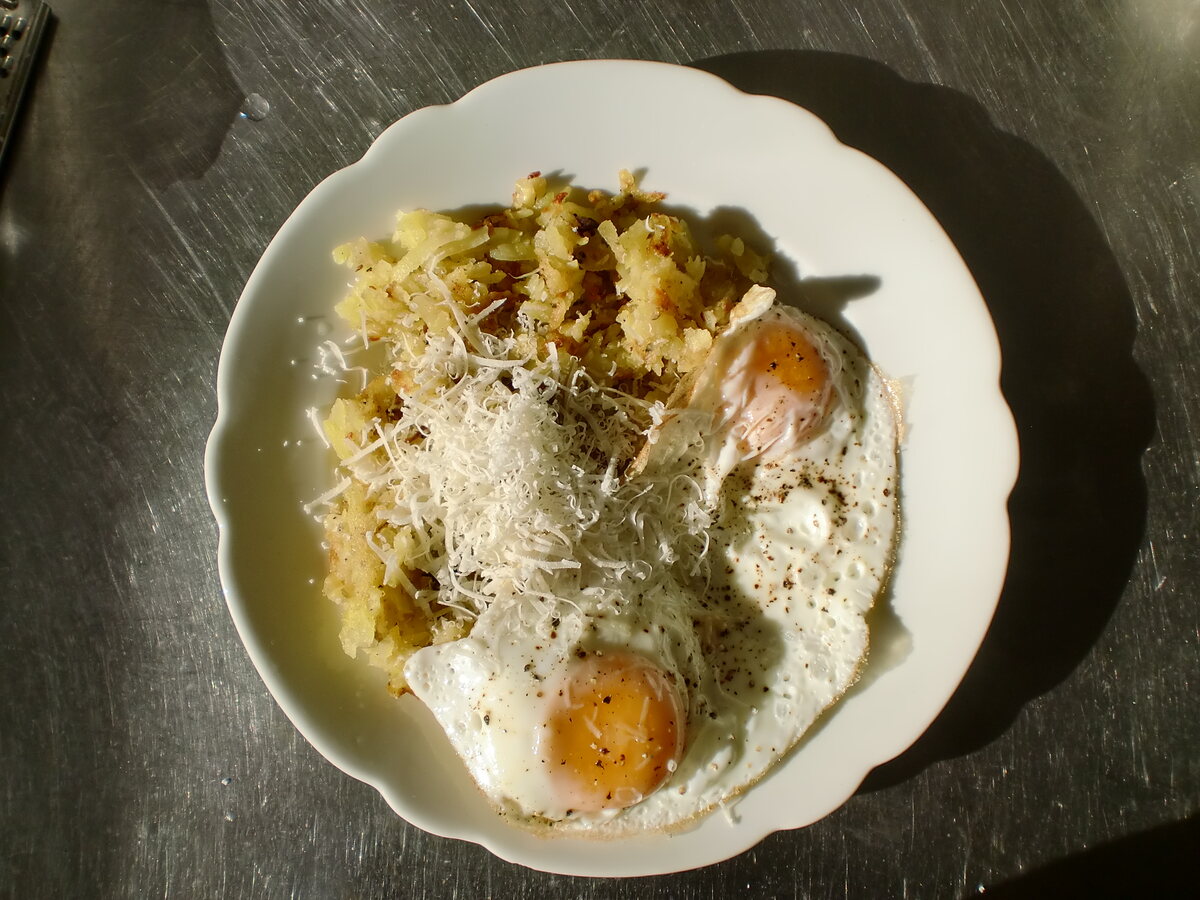 Potato pancake with two fried eggs and cheese